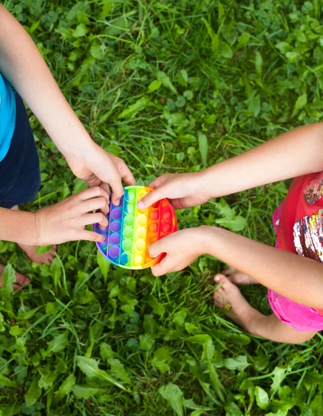 子供の手を丸い虹を保持することはおもちゃをポップ 遊んで 新しいフィジェットトレンディーなおもちゃ ストレス対策のおもちゃ シンプルなディンプル — ストック写真