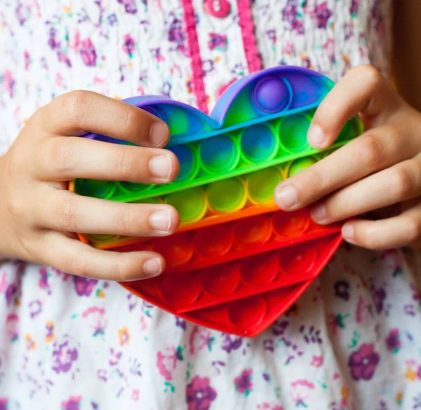 Stock image Girl holding heart shaped pop it toy. New fidget trendy toy. Antistress toy. Simple dimple.