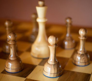 Siyah piyonlarla çevrili beyaz papaz. Satranç tahtasındaki tahta satranç taşları. Satranç oyunu.