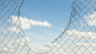 Kırık metal tel örgüler mavi gökyüzüne karşı. 