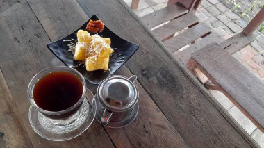 Kopi dan singkong keju. Kahve ve peynirli kızarmış manyok ahşap masada.
