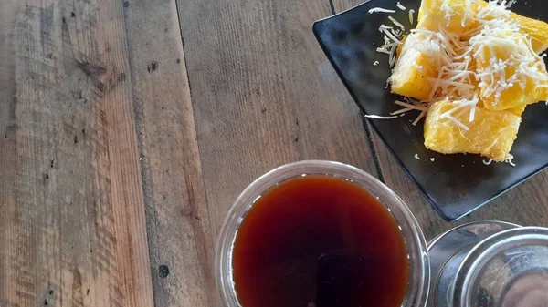 シンコン ケジュ 木製のテーブルの上にコーヒーとチーズがちりばめられた揚げキャッサバ — ストック写真