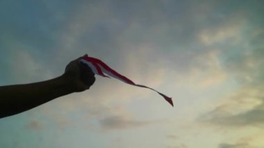 Eller kırmızı ve beyaz kurdele takıyor, gökyüzü arkaplanı, Endonezya bağımsızlık günü konsepti