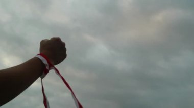 Eller kırmızı ve beyaz kurdele takıyor, gökyüzü arkaplanı, Endonezya bağımsızlık günü konsepti