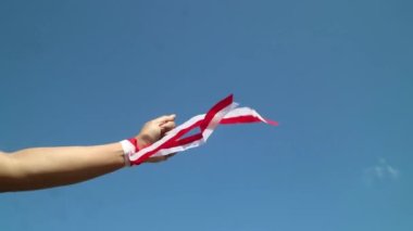 Eller kırmızı ve beyaz kurdele takıyor, gökyüzü arkaplanı, Endonezya bağımsızlık günü konsepti