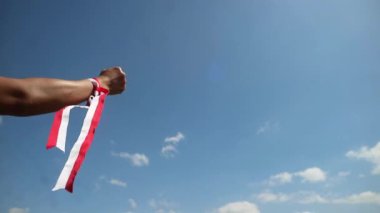 Eller kırmızı ve beyaz kurdele takıyor, gökyüzü arkaplanı, Endonezya bağımsızlık günü konsepti