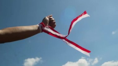 Eller kırmızı ve beyaz kurdele takıyor, gökyüzü arkaplanı, Endonezya bağımsızlık günü konsepti