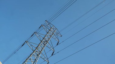 Elektrik direkleri ve kablolar aşağıdan gökyüzüne doğru görünüyor