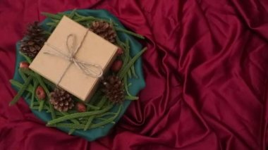 Noel arkaplanı 360 derece dönüş. Firavun yaprakları, kurumuş çam ve kırmızı arka planda dönen hediye kutusu. Yeni yıl hediyeleri, festival ve tatil alışverişi kavramı