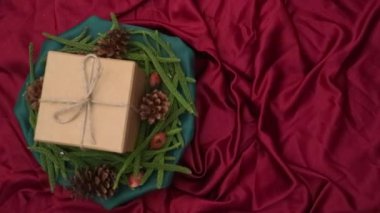 Noel arkaplanı 360 derece dönüş. Firavun yaprakları, kurumuş çam ve kırmızı arka planda dönen hediye kutusu. Yeni yıl hediyeleri, festival ve tatil alışverişi kavramı