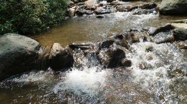 Yakından akan su, farklı boyutlarda taşları olan bir nehirden akar. Kayalık nehir.