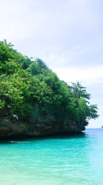Malang Endonezya 'daki Teluk Asmara plajının manzarası, deniz kenarındaki kayalıklar ve kayalar gün doğumunda veya batımında güzel bulutlar.