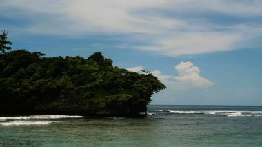 Malang Endonezya 'daki Teluk Asmara plajının manzarası, deniz kenarındaki kayalıklar ve kayalar gün doğumunda veya batımında güzel bulutlar.