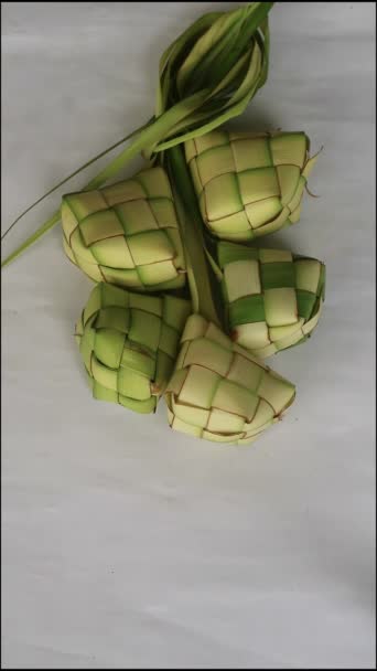 ケッチャンは白い背景で孤立した 若いココナッツの葉から作られたラッパーで包まれた米から作られた典型的な料理 エイドアルフィトの祭りの間に伝統的なモスレムの食べ物 — ストック動画