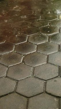 Şiddetli yağmur damlaları desenli zemindeki su birikintilerine düşüyor.