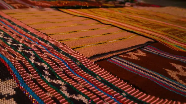 Close up side view handmade woven fabric with unique pattern from Indonesia, selective focus, multicolour textured textile background