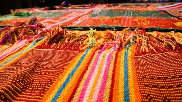 Close up side view handmade woven fabric with unique pattern from Indonesia, selective focus, multicolour textured textile background