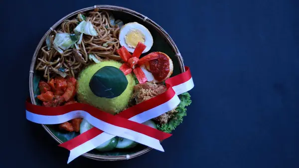 stock image Tumpeng Merah Putih, yellow cone shaped rice with red and white flag or ribbon made during Indonesia Independence day every August 17, with black background copy space