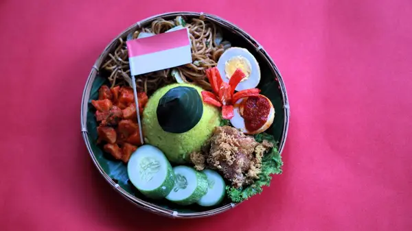 stock image Tumpeng Merah Putih, yellow cone shaped rice with red and white flag or ribbon made during Indonesia Independence day every August 17, with red background copy space