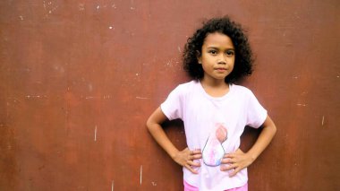 Kıvırcık saçlı, pembe tişörtlü, izole edilmiş koyu kırmızı saçlı, gülümseyen küçük Asyalı kız.