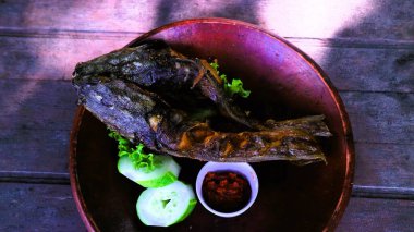 Pecel lele, geleneksel Endonezya yemeği kızarmış Lele aromatik kemangi yaprağı ve ahşap masa üzerinde acı biber sosu ile servis edilir.