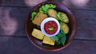 Endonezya geleneksel yemekleri, dilimlenmiş patlıcan ve ahşap tabakta kırmızı biber sosuyla servis edilen kızarmış tofu ve tempeh 'den oluşur.