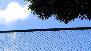 Wire net with blue sky background, used as a field fencing for safety clipart