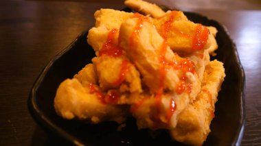 Siyah tabakta servis edilen domates soslu çıtır tofu, Endonezya yemeği.