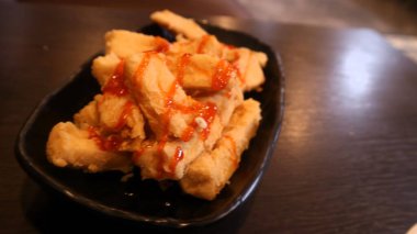 Siyah tabakta servis edilen domates soslu çıtır tofu, Endonezya yemeği.