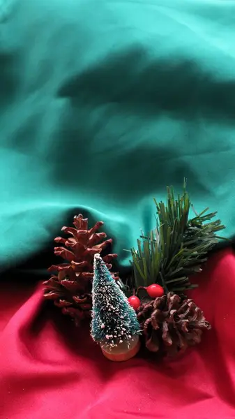 Kurumuş çam çiçekleri, şirin noel ağaçları ve yeşil ve kırmızı arka planda köknar yaprakları.