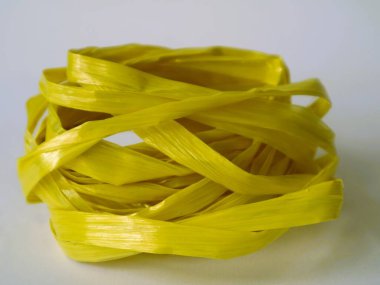 Beyaz arka planda izole edilmiş sarı bir rafya ipi rulosu. ev dekorasyonu yaratıcılık ekipmanı