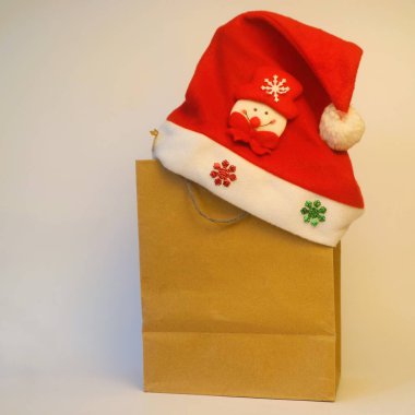 Hediye ve Noel Baba şapkası beyaz arka planda izole edilmiş kağıt alışveriş torbası, fotokopi alanı, Noel kutlaması konsepti.