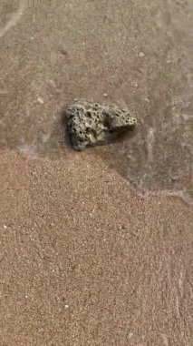 Sahildeki küçük dalgalar, kıyıdaki küçük dalgalar. Sakin ve sığ sularda hafif dalgalar dans etti. Yumuşak, mırıltılı dalgalar yatıştırıcı bir ninni yarattı. Kondang Merak Sahili, Malang, Doğu Java Endonezya