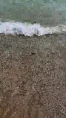 Sahildeki küçük dalgalar, kıyıdaki küçük dalgalar. Sakin ve sığ sularda hafif dalgalar dans etti. Yumuşak, mırıltılı dalgalar yatıştırıcı bir ninni yarattı. Kondang Merak Sahili, Malang, Doğu Java Endonezya