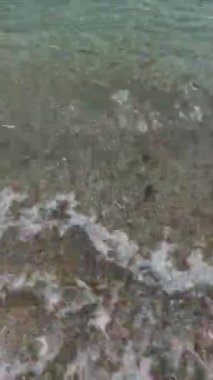 Sahildeki küçük dalgalar, kıyıdaki küçük dalgalar. Sakin ve sığ sularda hafif dalgalar dans etti. Yumuşak, mırıltılı dalgalar yatıştırıcı bir ninni yarattı. Kondang Merak Sahili, Malang, Doğu Java Endonezya