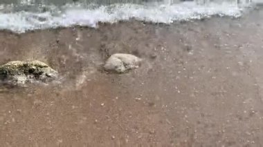 Sahildeki küçük dalgaların 4K videosu, kıyıdaki küçük dalgalar. Sakin ve sığ sularda hafif dalgalar dans etti. Malang Endonezya 'daki Kondang Merak Sahili
