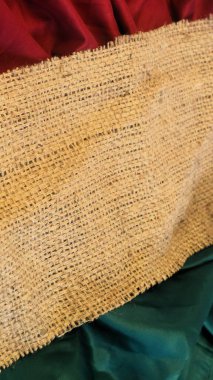 Yeşil ve kırmızı düz kumaşlı, kırsal bir vintage çuval bezi, minimalist noel kutlamaları için kopya alanı desenli arka plan