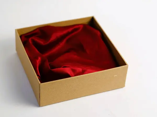 Bir minimalist, içinde kırmızı bez bulunan karton hediye kutusunu açtı. Ürün fotoğrafçılık tabanı için. El değmemiş beyaz bir arka planda izole edilmiş.