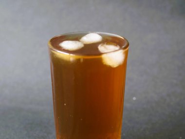 Kristal berrak bardakta zarif bir şekilde servis edilen ferahlatıcı bir bardak buzlu çay. Buzlu çayın kehribar rengi bardağın berraklığıyla güzel bir tezat oluşturuyor. Klasik bir buzlu çay, zamansız bir bardakta servis edilir, rahatlatıcı..