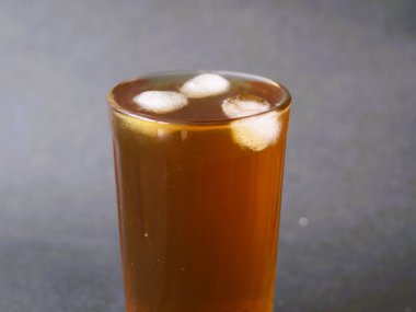 Kristal berrak bardakta zarif bir şekilde servis edilen ferahlatıcı bir bardak buzlu çay. Buzlu çayın kehribar rengi bardağın berraklığıyla güzel bir tezat oluşturuyor. Klasik bir buzlu çay, zamansız bir bardakta servis edilir, rahatlatıcı..