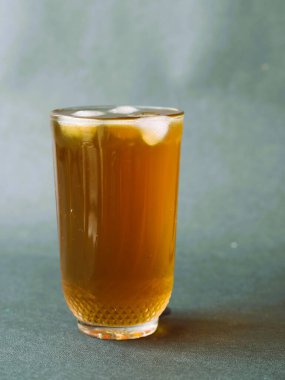 Kristal berrak bardakta zarif bir şekilde servis edilen ferahlatıcı bir bardak buzlu çay. Buzlu çayın kehribar rengi bardağın berraklığıyla güzel bir tezat oluşturuyor. Klasik bir buzlu çay, zamansız bir bardakta servis edilir, rahatlatıcı..