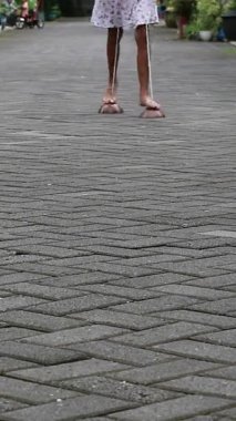 Genç bir kız Hindistan cevizi kabuğunu geleneksel Endonezya oyunlarını sergilemek için yaratıcı bir şekilde kullanıyor. Küçük bir kız hindistan cevizi kabuğunda dengede duruyor, sınırlarını zorluyor. Çocukluk sevincinin sembolü.