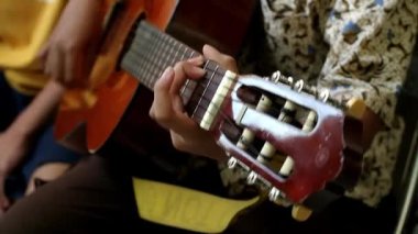 Gitar akorlarında ustalaşan genç eller, adanmışlık ve yeni bir beceri öğrenme tutkusu. Gitar çalan bir gencin elleri, müzik becerilerini ve farkındalığını geliştirmek için yeni yılı sembolize ediyor. Müzik dünyasını keşfetmek