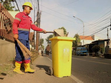 Roadside cleaning: workers use brooms and bins to maintain clean streets, playing a crucial role in public health and urban sanitation. Workers with brooms and trash bins upkeep roadside cleanliness by sweeping. clipart