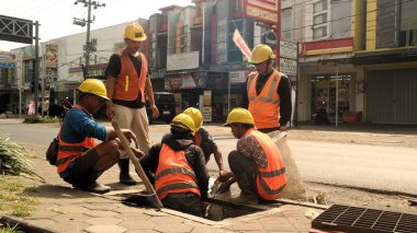 Endonezyalı işçiler yağmur mevsiminde selleri öngören drenaj sistemlerini temizliyorlar. Endonezyalı işçiler şiddetli yağmur mevsiminde selleri azaltmak için proaktif olarak temiz drenaj yapıyorlar.