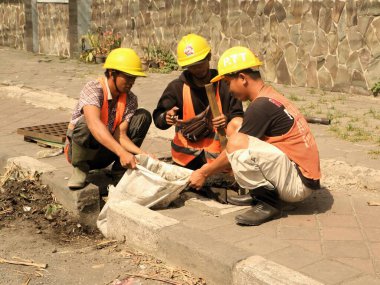 Endonezyalı işçiler yağmur mevsiminde selleri öngören drenaj sistemlerini temizliyorlar. Endonezyalı işçiler şiddetli yağmur mevsiminde selleri azaltmak için proaktif olarak temiz drenaj yapıyorlar.