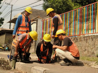 Endonezyalı işçiler yağmur mevsiminde selleri öngören drenaj sistemlerini temizliyorlar. Endonezyalı işçiler şiddetli yağmur mevsiminde selleri azaltmak için proaktif olarak temiz drenaj yapıyorlar.