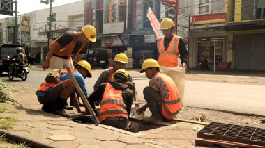 Endonezyalı işçiler yağmur mevsiminde selleri öngören drenaj sistemlerini temizliyorlar. Endonezyalı işçiler şiddetli yağmur mevsiminde selleri azaltmak için proaktif olarak temiz drenaj yapıyorlar.