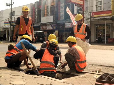 Endonezyalı işçiler yağmur mevsiminde selleri öngören drenaj sistemlerini temizliyorlar. Endonezyalı işçiler şiddetli yağmur mevsiminde selleri azaltmak için proaktif olarak temiz drenaj yapıyorlar.