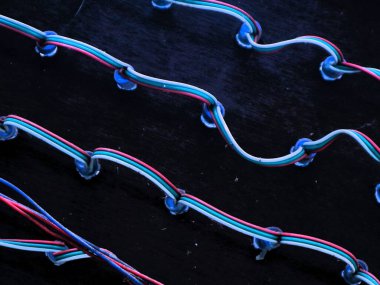 Parlak renkli LED kabloları koyu arkaplan üzerinde keskin bir kontrast. LED kablolar zıt bir karanlık yüzey üzerinde renkli devreler sergiliyor. Karanlık soyut tasarım için uygun.